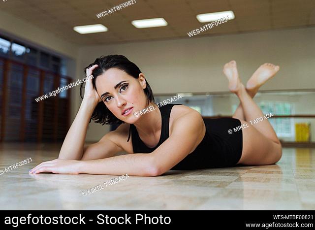 Ballerina with hand in hair lying on floor at dance studio