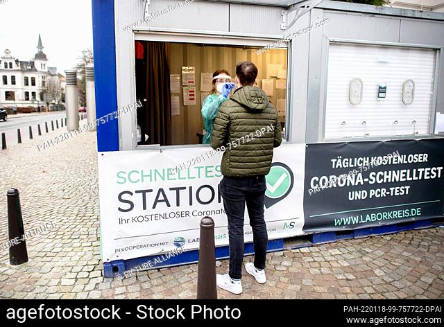 18 January 2022, Lower Saxony, Oldenburg: An employee at a testing station in the city center takes a swab from a young man