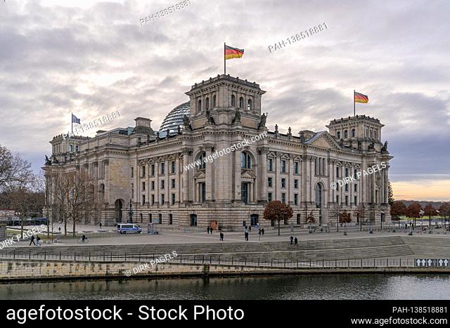 December 28, 2020, Berlin, the Reichstag building by master builder Paul Wallot on the Platz der Republik with flags on the day with cloudy skies