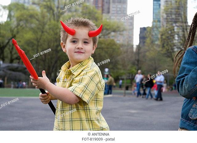 A young boy wearing devils horns and holding a pitchfork, Central Park, New York City