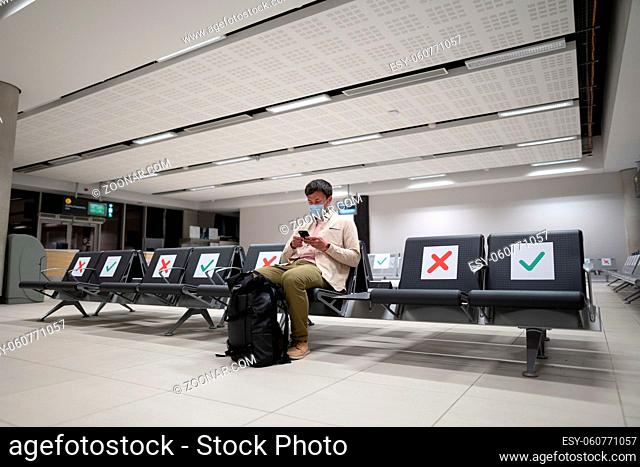 Man wearing protective mask upset by cancellation flight, writes message to his family, sitting in empty terminal at airport of Cyprus, Paphos city