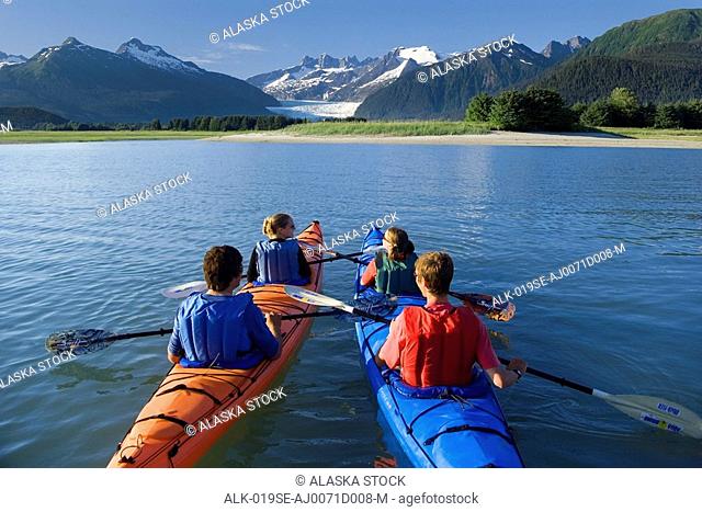 Kayakers kayaking in double sea-kayaks near Juneau in Inside Passage with view of Mendenhall Glacier Alaska