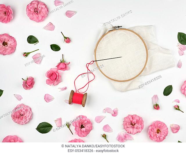 round wooden hoop and a red thread with a needle, concept of embroidery products, top view