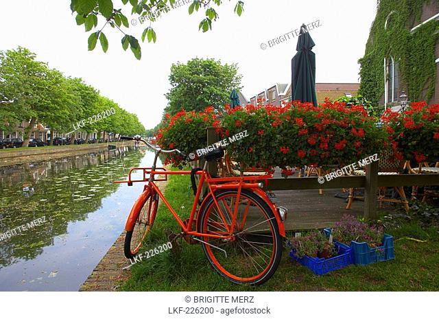 Red bicycle standing at the banks of a gracht canal, Weesp, Netherlands, Europe