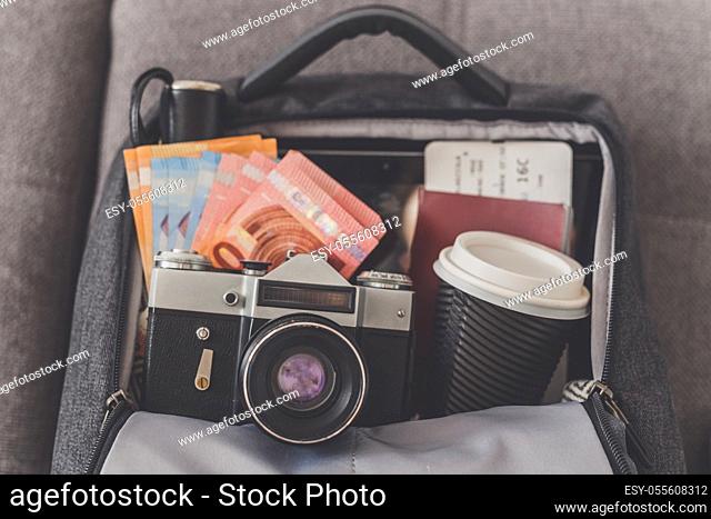 Opened backpack with things needed for travel, camera, money, passport and tickets