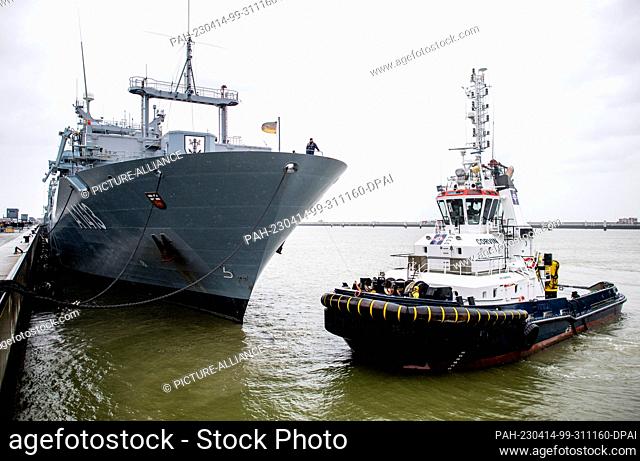 12 April 2023, Lower Saxony, Wilhelmshaven: The tug ""Corvin"" connects a tow line with the task force supply ship ""Bonn"" in the harbor at the naval base...