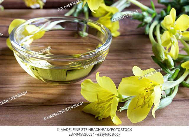 Evening primrose oil in a glass bowl, with blooming evening primrose in the foreground