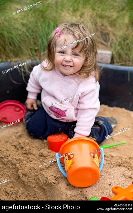 Little girl is playing in the sandpit