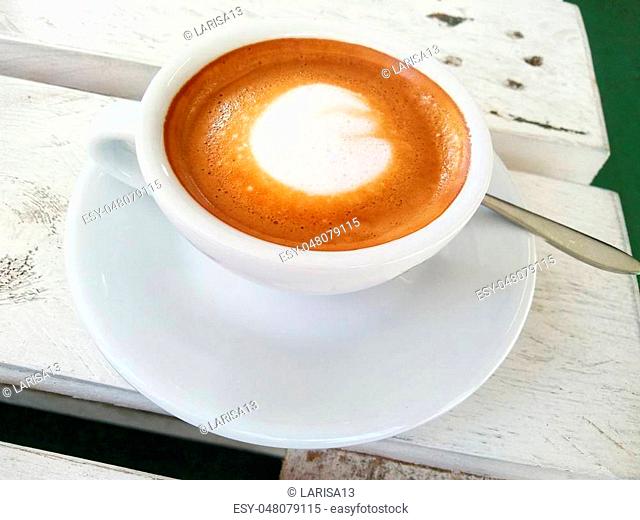 White coffee Cup with a gourmet coffee on the table of the wooden Board cracked