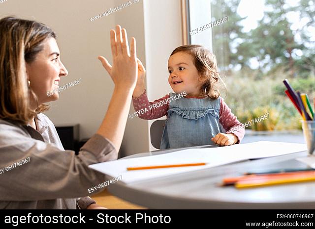 mother with daughter drawing and making high five