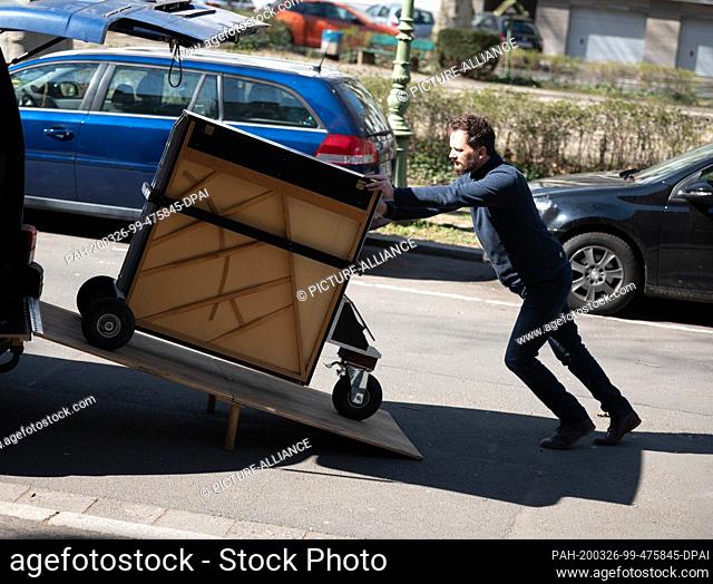 25 March 2020, Rhineland-Palatinate, Mainz: Simon Höneß, pianist, composer and street musician, loads his rolling piano from the van