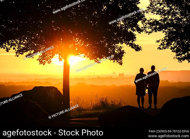 05 September 2023, Lower Saxony, Hanover: A couple stands on the Kronsberg at sunrise. Photo: Julian Stratenschulte/dpa. - Hanover/Lower Saxony/Germany