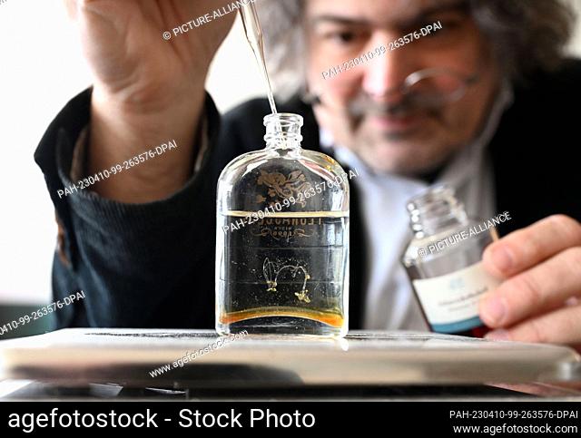 PRODUCTION - 03 April 2023, Baden-Württemberg, Karlsruhe: Perfumer Roland Tentunian adds an essential oil to a bottle of alcohol during a recipe development for...