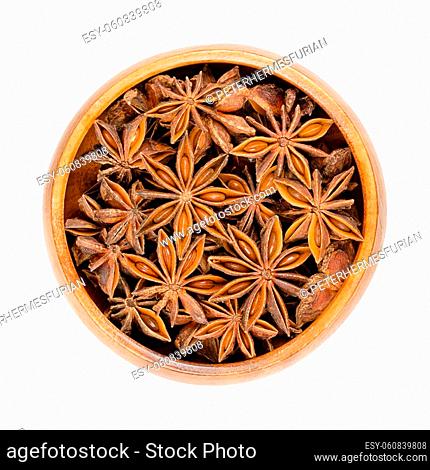 Star anise fruits and seeds, in a wooden bowl. Also known as staranise, star aniseed or badian. Dried, star-shaped pericarps of Illicium verum