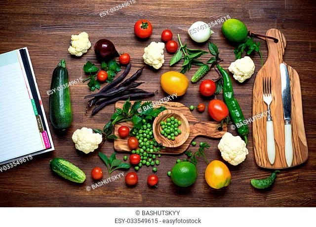 Healthy food. Herbs and vegetables on wooden table with recipe book