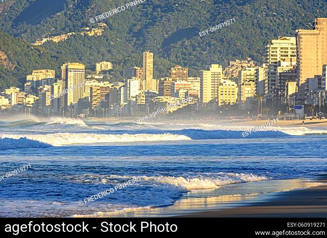 Sunrise on Ipanema beach in Rio de Janeiro with the sea, forest, waves and city buildings