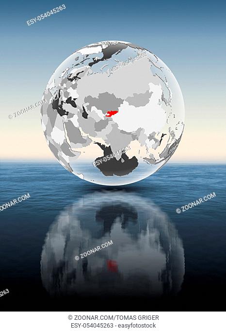 Kyrgyzstan in red on translucent globe floating above water. 3D illustration