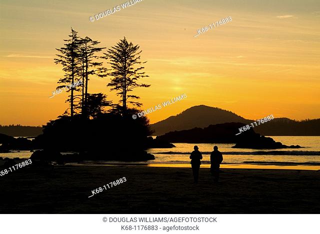 couple walks on the beach on Flores Island, BC, at sunset