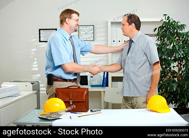 Architects working at office - shaking hands, smiling
