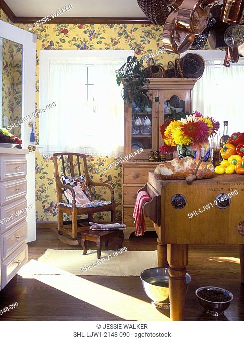 KITCHEN -Butcher block table with fall flowers, bread , vegetables, antique hutch with baskets, dishware, yellow floral wallpaper, copper pots hanging from rack