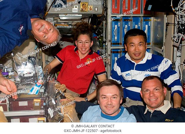 Five of the ten crewmembers on the International Space Station pose for a photo near the galley in the Zvezda Service Module while Space Shuttle Discovery...