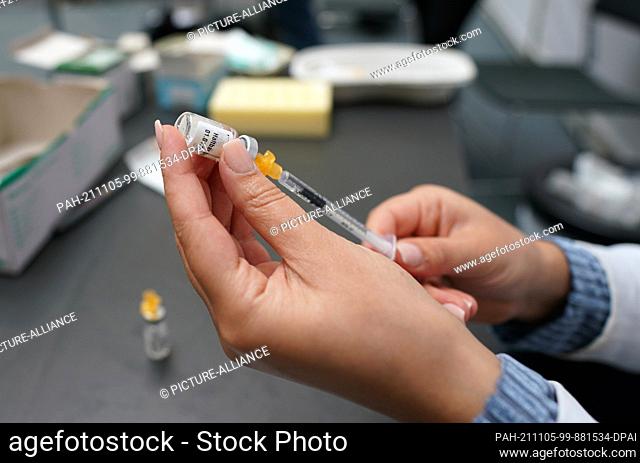 05 November 2021, Hamburg: A member of the Mobile Immunization Team draws up a syringe of vaccine at the Hamburg State and University Library