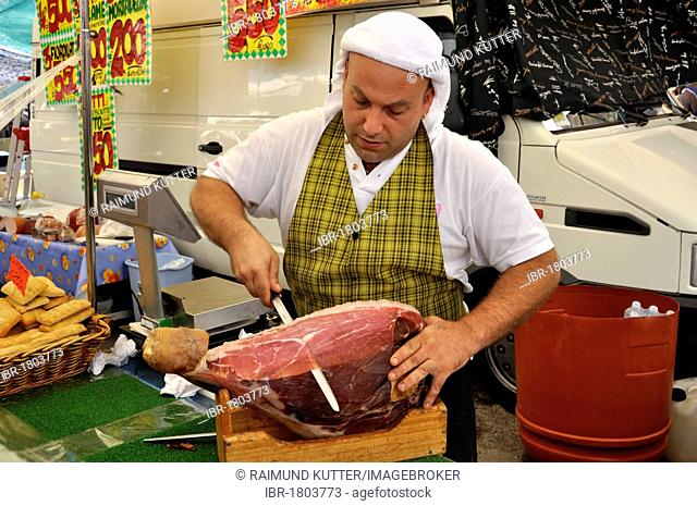 Seller with Italian ham or Prosciuto at a specialties stand on the farmers market, Rome, Lazio, Italy, Europe