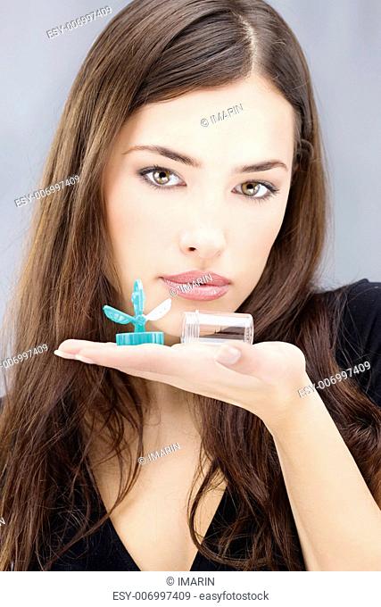 Young woman holding contact lenses wash container on hand in front of her face