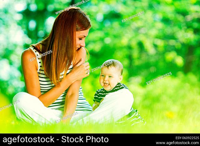 Happy mother and daughter relaxing sitting on grass background spring meadow