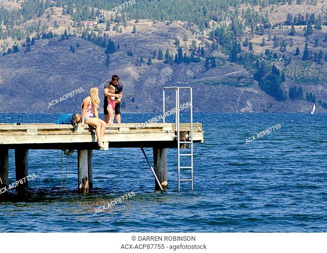 Young family fishes off the wharf at Rotary Park in Summerland, in the Okanagan region of British Columbia, Canada