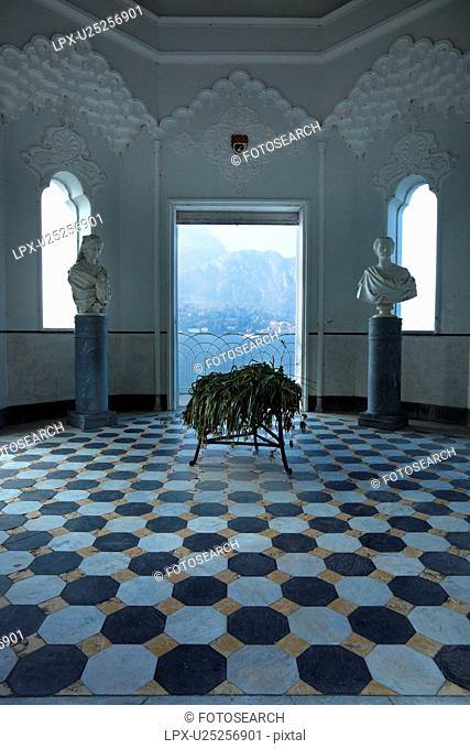 Interior of Tempio at Villa Melzi with ornate stucco interior, black and white geometric pattern of floor, arched windows and doorway with view onto Lake Como