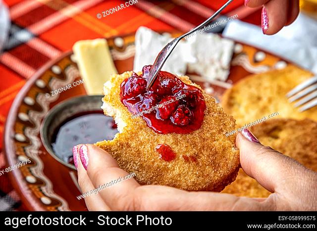 A woman's hand holds a fried slice of bread with jam at breakfast