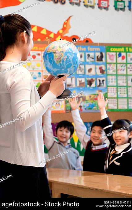Teacher teaching geography to schoolchildren with a globe