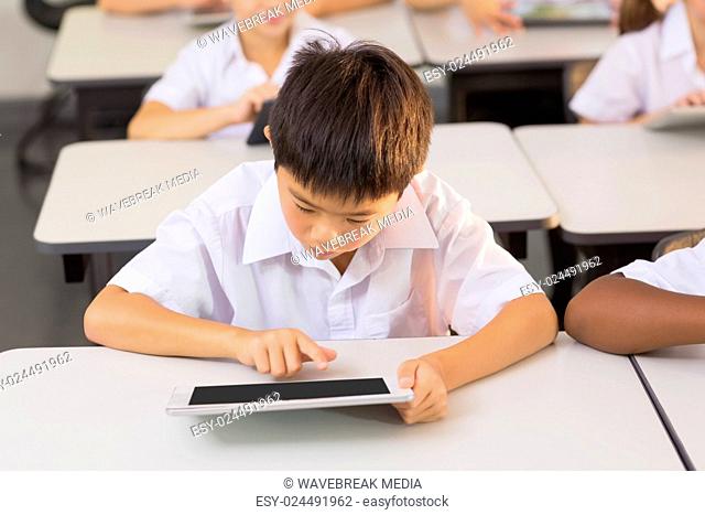 Schoolboy using digital tablet in classroom