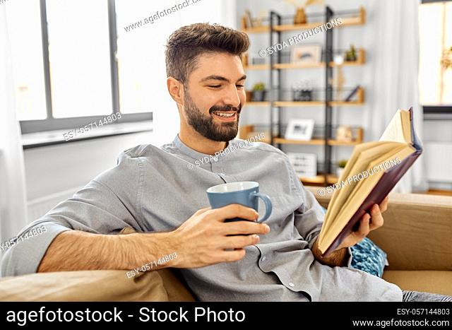 man reading book and drinking coffee at home
