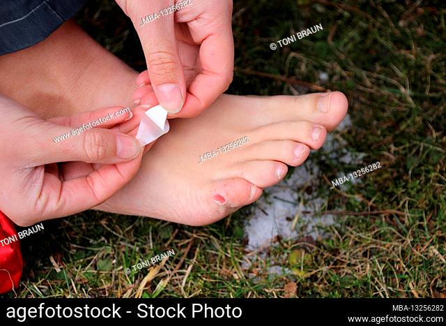 Woman treats blister on the foot while hiking