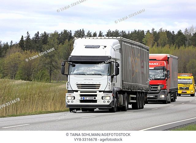 Salo, Finland - May 3, 2019: Colourful heavy trucks driving along rural highway on a cloudy day
