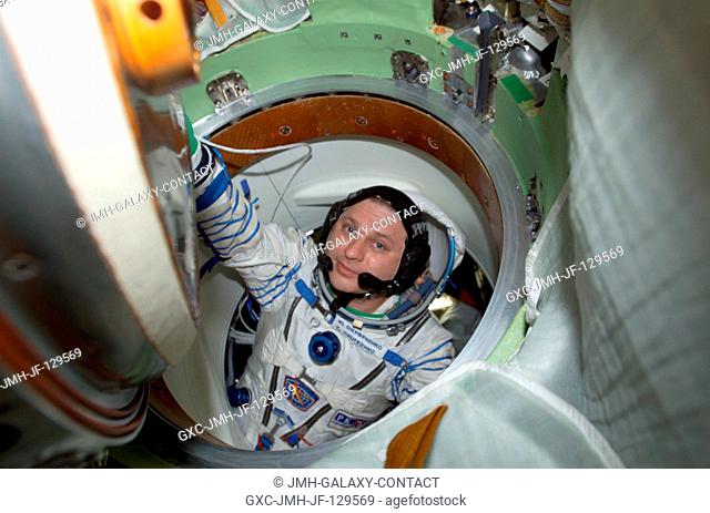 Cosmonaut Yury I. Onufrienko, Expedition Four mission commander, wearing a Russian Sokol suit, moves through a hatch in the Soyuz 3 spacecraft that is docked to...