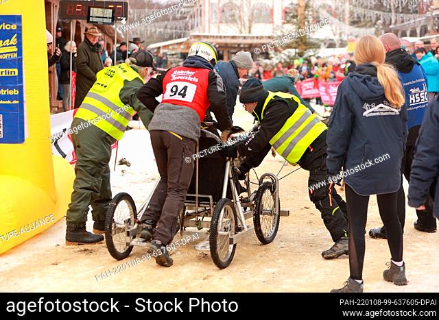 08 January 2022, Saxony-Anhalt, Hasselfelde: At the sled dog race in the western town of Pullman City Harz, helpers in the starting area hold a team until the...