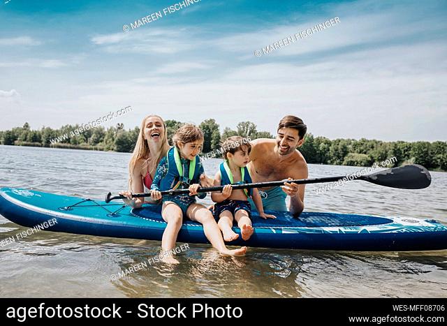 Children holding oar by parents in lake on weekend