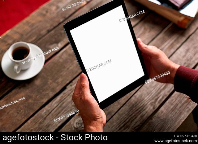 Digital tablet computer with isolated screen in male hands over cafe background - table, cup of coffee..
