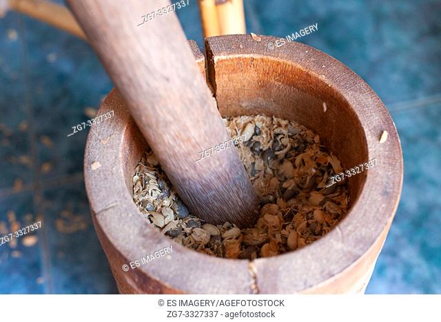 Using a mortar and pestle to remove shells (Cascara) from coffee beans