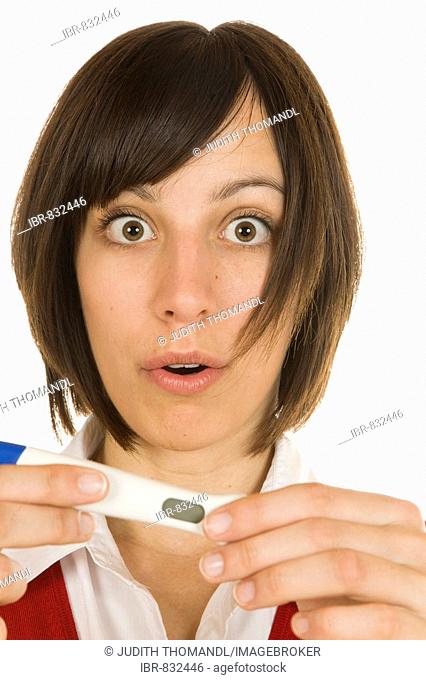 Surprised 20-year-old woman holding a pregnancy test