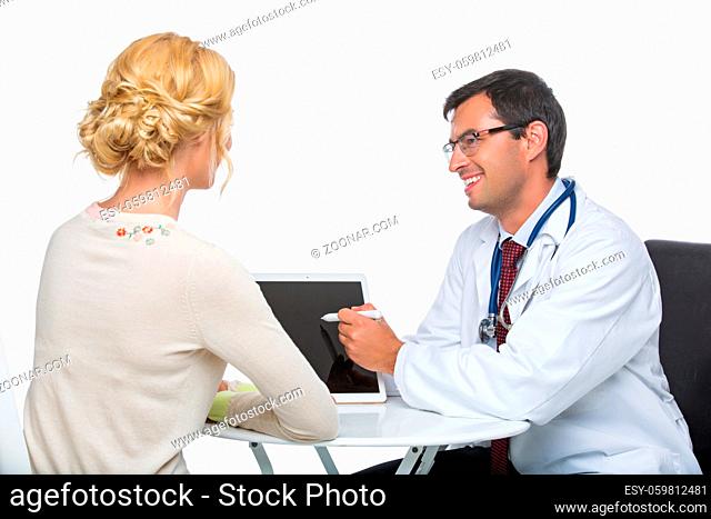 handsome doctor in white coat explaining something with tablet computer to beautiful woman patient. studio shot. copy space