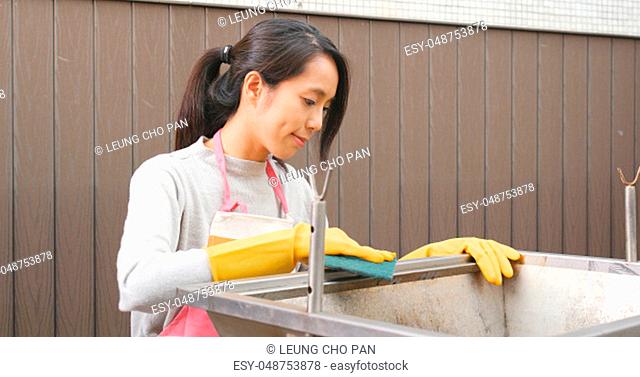 Woman cleaning of barbecue oven at outdoor with Scour Pad