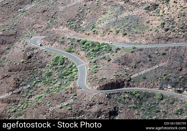 Curved winding road with a white cars in the mountains in Gran Canaria, Spain