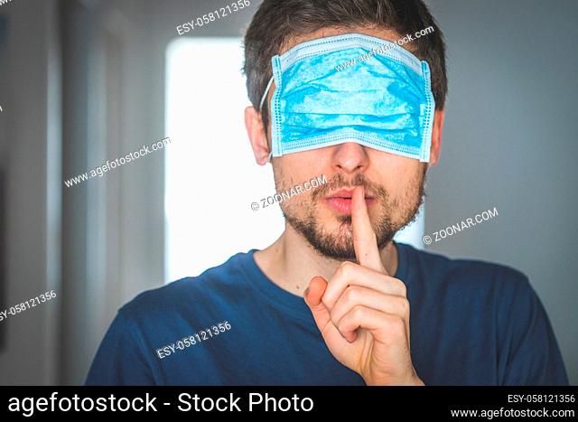 Young angry man with face mask over the eyes is doing a psst! gesture