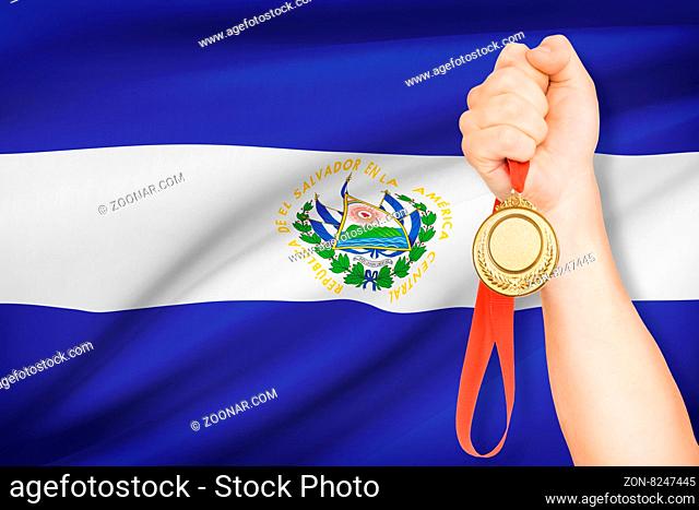 Sportsman holding gold medal with flag on background - Republic of El Salvador
