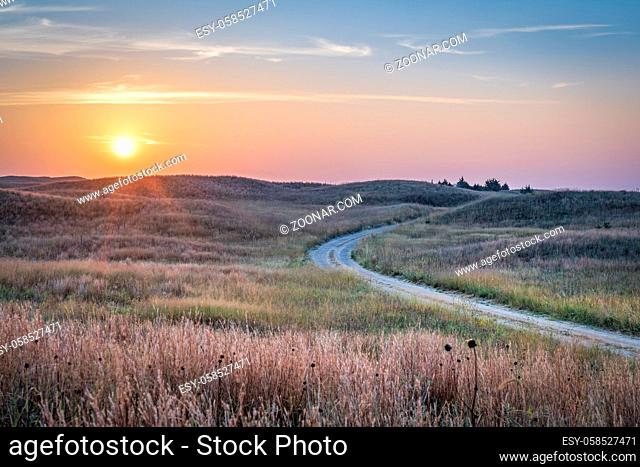 hazy sunrise over Nebraska Sandhills with a dirt sandy road at Nebraska National Forest, fall scenery affected by wildfire smoke from Colorado and Wyoming