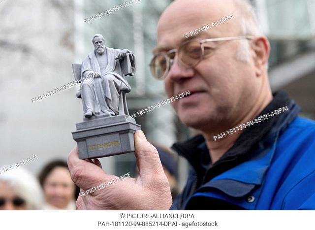 14 November 2018, Bavaria, München: The former employee of the Munich city drainage Ben Tax holds a miniature replica of Max von Pettenkofer's monument in his...